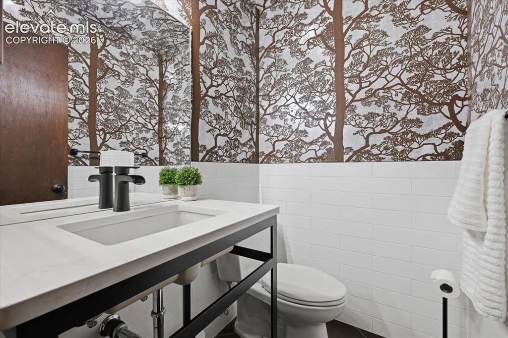 Image 23 of 50: Main Level Powder room with original decorative wallpaper with white subway