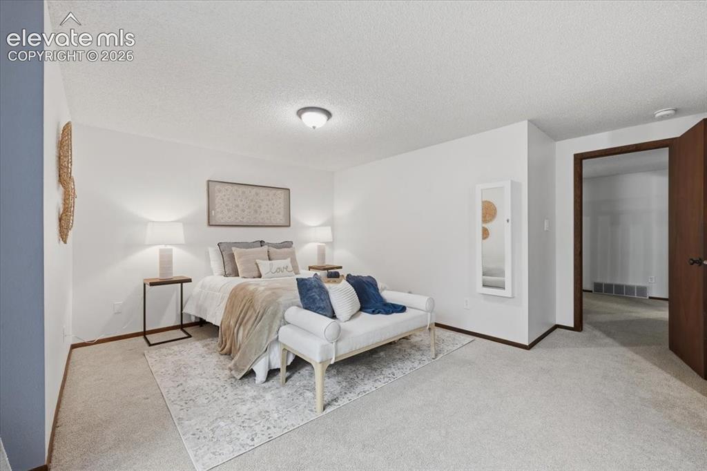 Image 25 of 50: Neutral wall finishes with a ceiling mounted light fixture. Space for bed a
