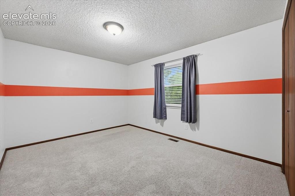 Image 29 of 50: Bedroom 2 with overhead lighting, blinds and a window overlooking the backy