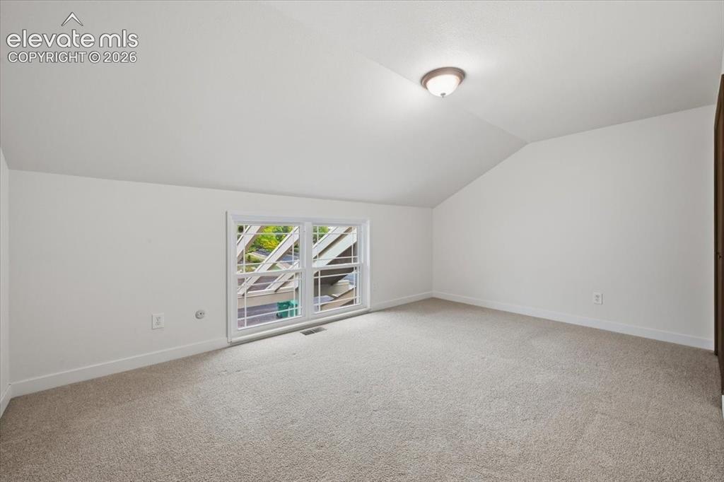 Image 35 of 50: Bedroom 4 - Neutral carpeting and white walls with a sloped ceiling