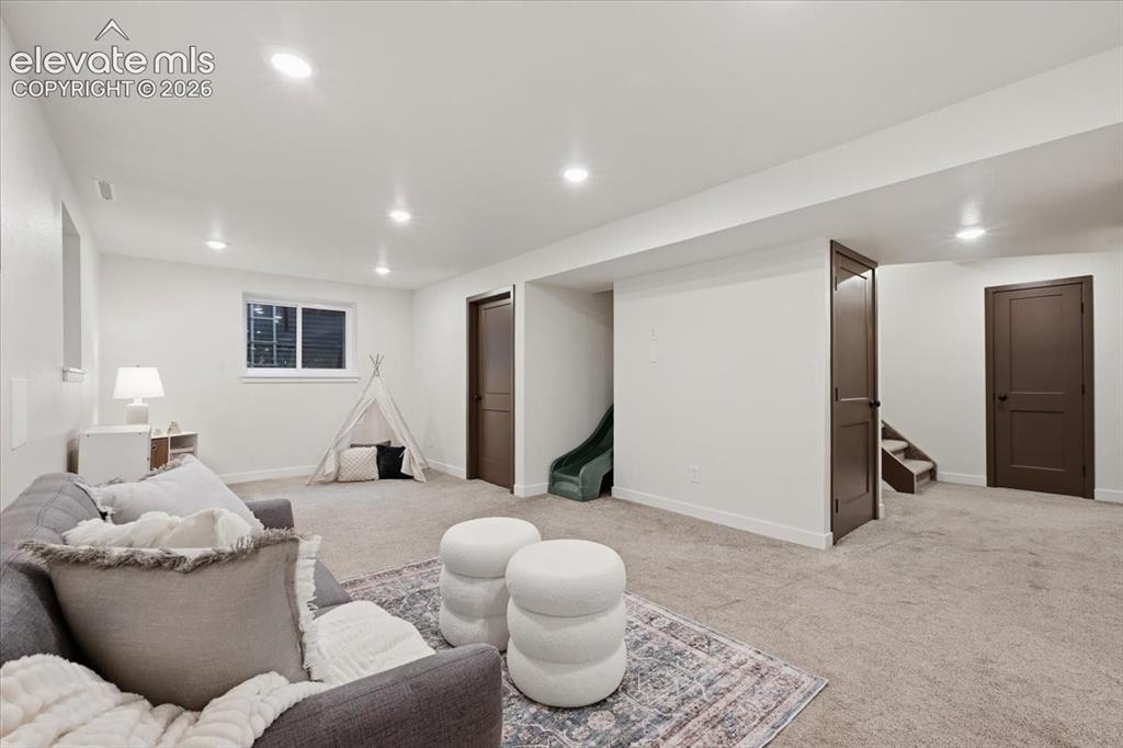 Image 37 of 50: Recessed lighting throughout, light-toned carpeting, white painted walls, a