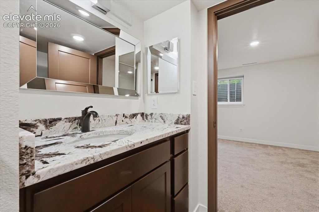 Image 40 of 50: Vanity with a granite countertop, undermount sink, and dark wood-finish cab