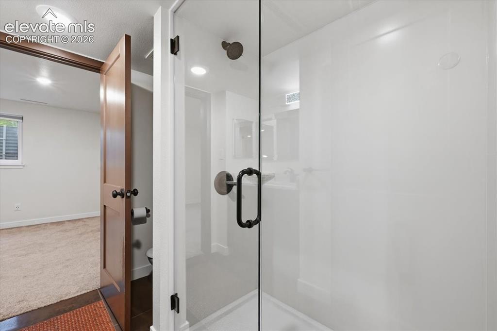 Image 41 of 50: Frameless glass shower enclosure, recessed lighting, and custom flooring