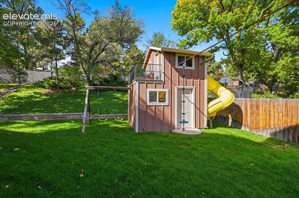 Image 50 of 50: Expansive grassy yard featuring a multi-level playhouse with a spiral slide