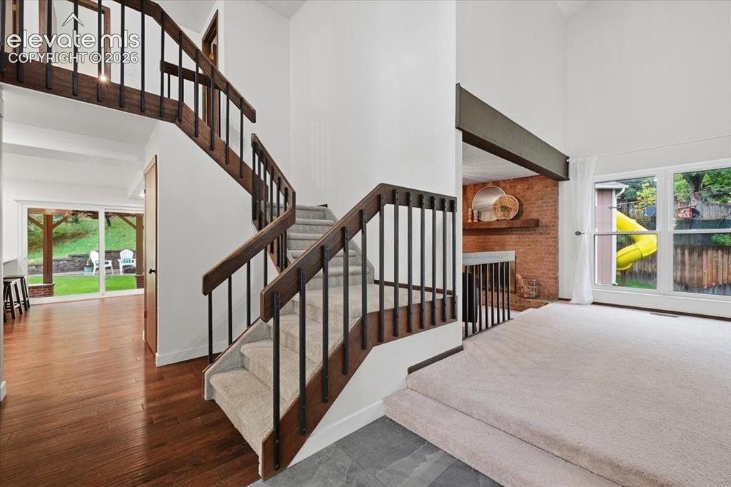 Image 8 of 50: Hardwood flooring, carpeted stairs with Vaulted Entry, brick-clad interior 