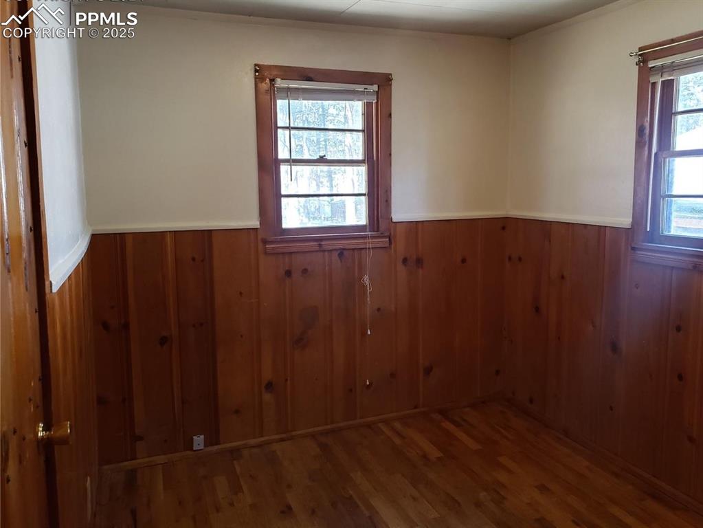 Image 15 of 20: Empty room featuring wood walls, a wainscoted wall, and wood finished floor