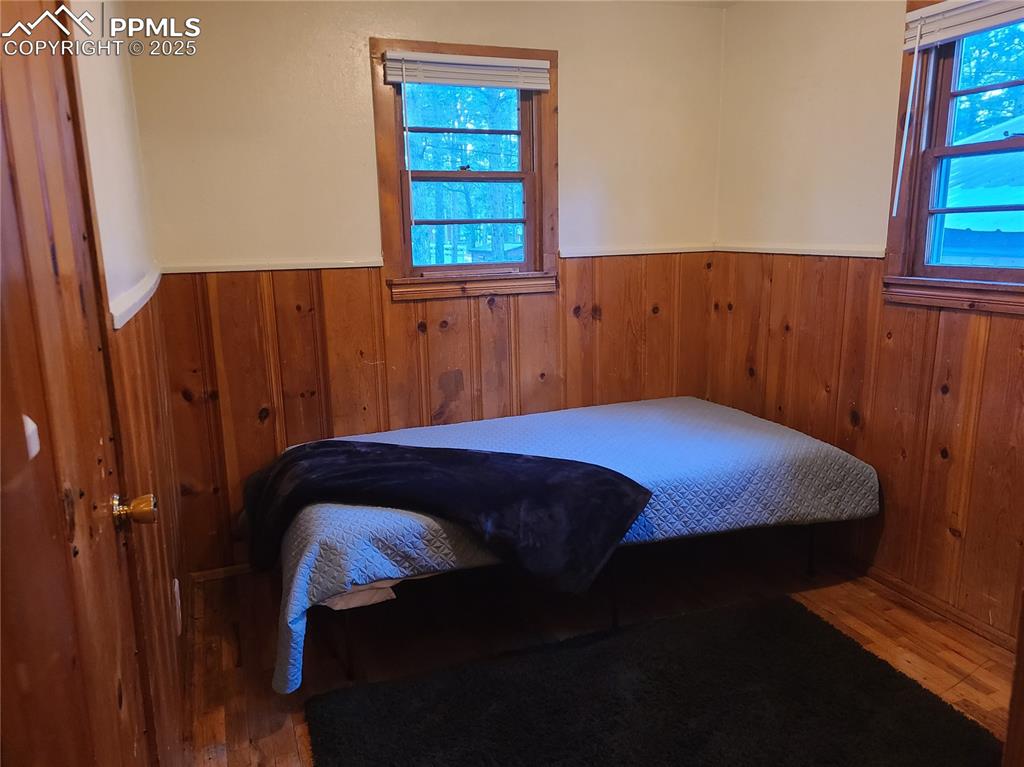 Image 19 of 20: Bedroom with wood walls, a wainscoted wall, and wood finished floors