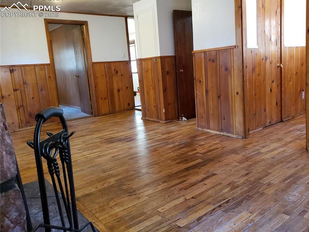 Image 6 of 20: Empty room with wood walls, wainscoting, and wood finished floors