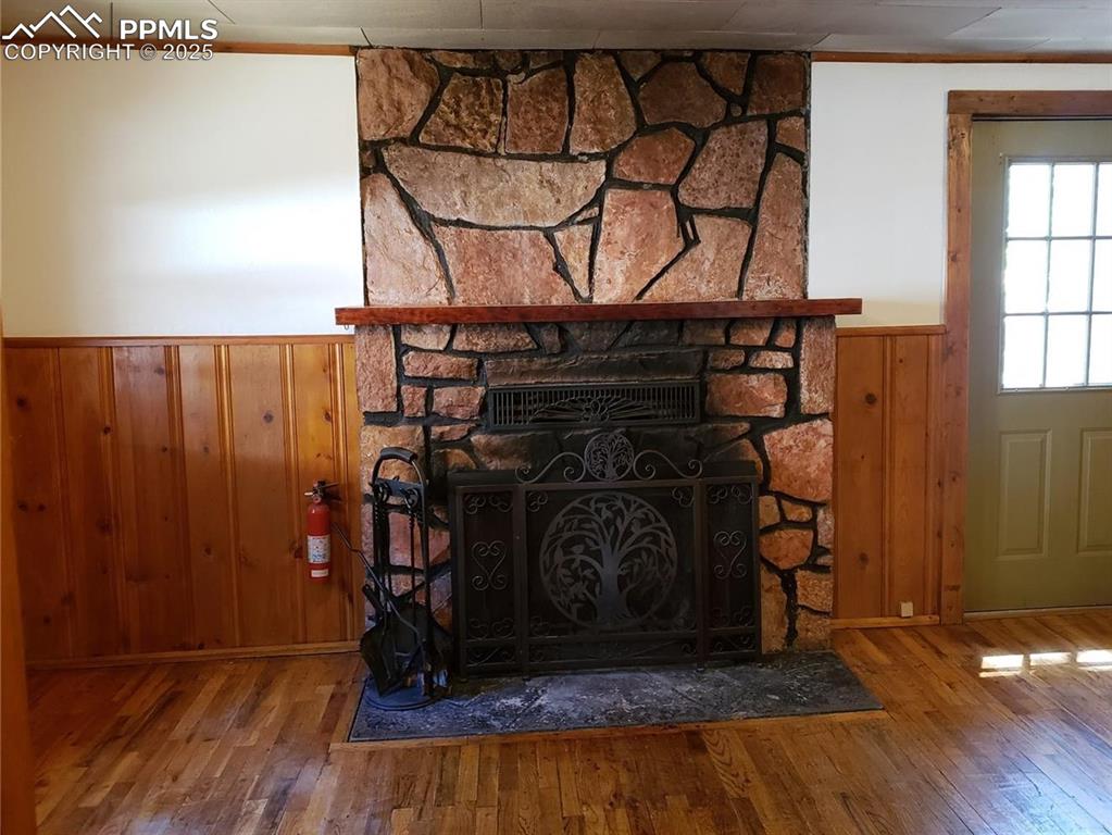 Image 8 of 20: Room details with a fire extinguisher, a stone fireplace, wainscoting, and