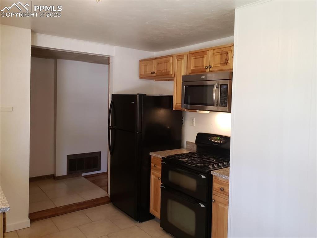 Image 9 of 20: Kitchen with visible vents, black appliances, light tile patterned flooring