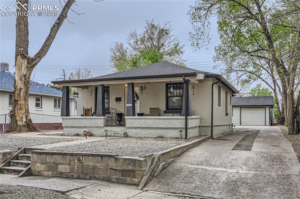 Caption: View of front of property featuring an outbuilding, stucco siding, covered porch, and concrete drive