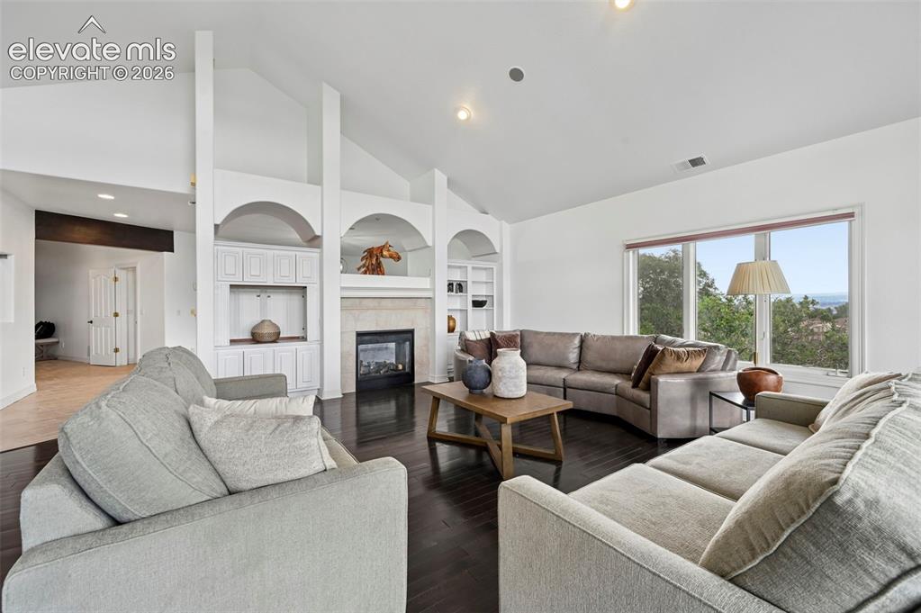 Image 12 of 45: Spacious living area featuring vaulted ceilings and dark wood-finish floori