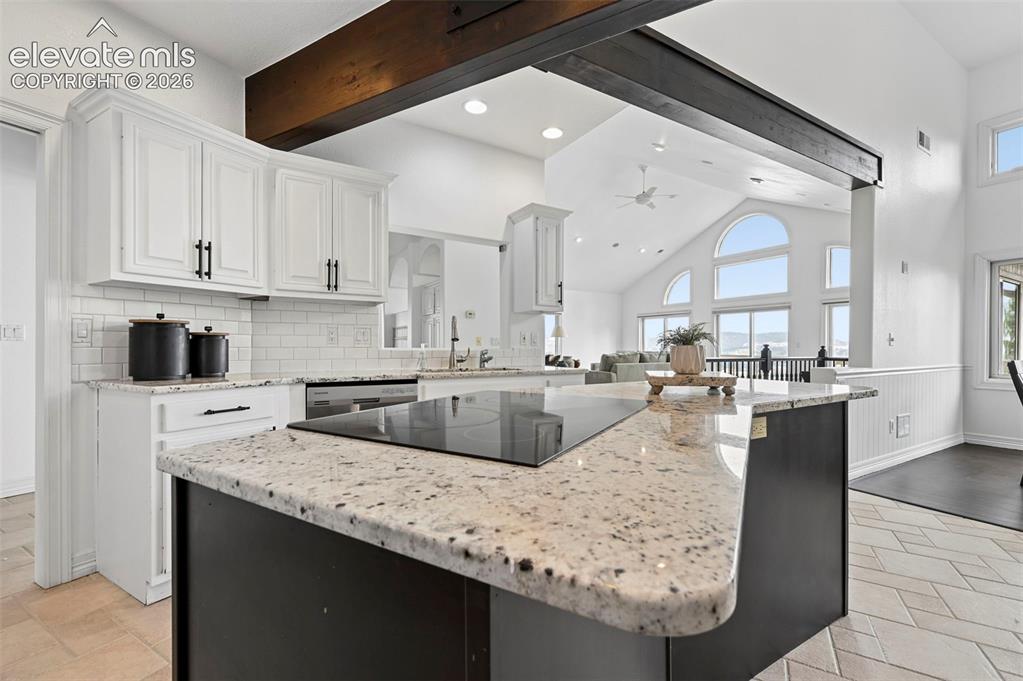 Image 14 of 45: Kitchen island with integrated cooktop, granite countertop, and dark cabine