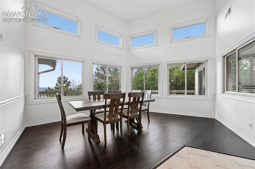Image 17 of 45: Dining area featuring high ceilings, dark wood-finish flooring, white beadb