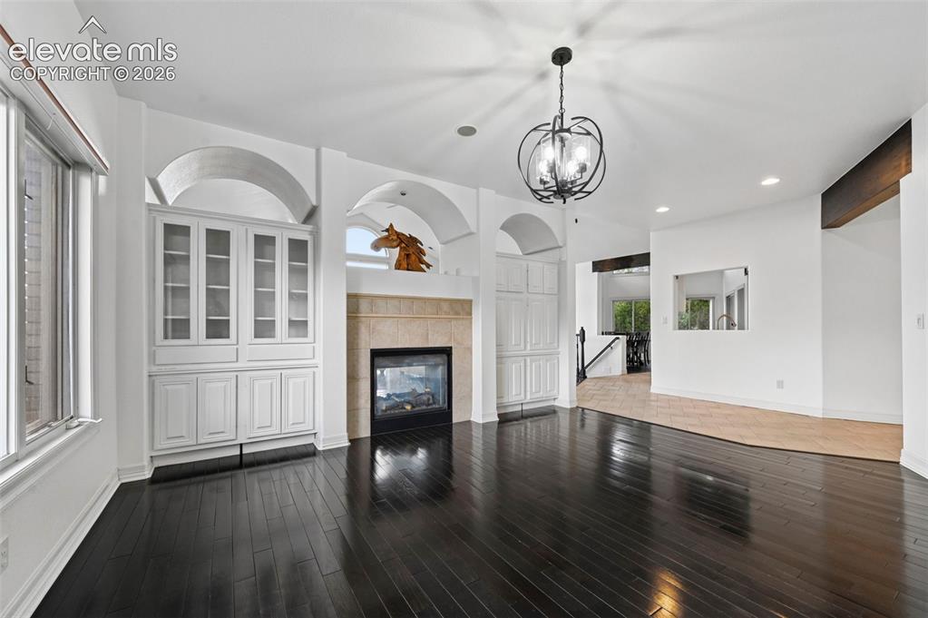 Image 18 of 45: Dark wood-finish flooring, built-in cabinetry with glass display doors, arc