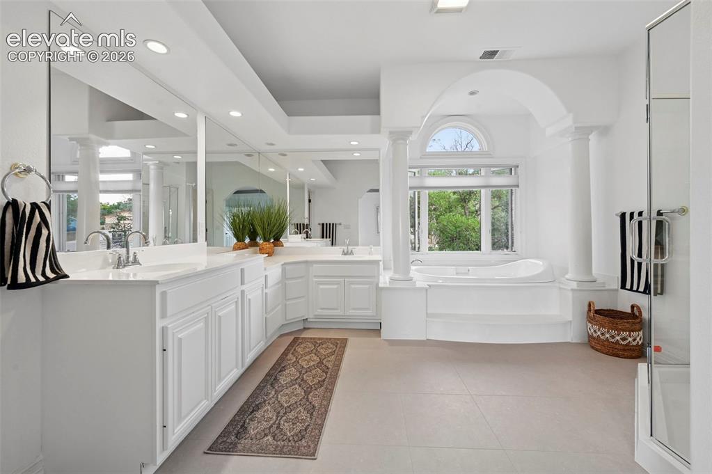 Image 22 of 45: Spacious bathroom featuring a built-in soaking tub, arched window, and dual
