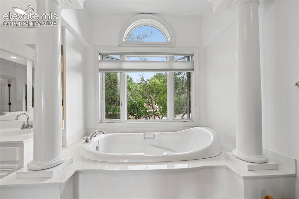 Image 23 of 45: Built-in soaking tub with deck-mounted fixtures, framed by decorative colum