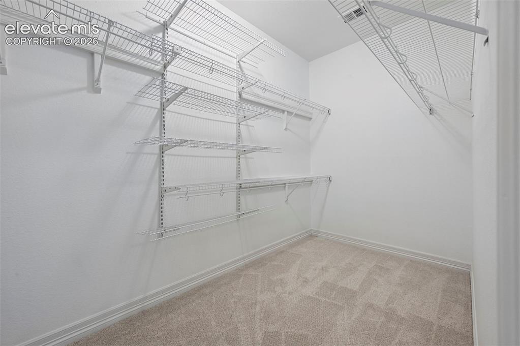 Image 25 of 45: Walk-in closet featuring white wire shelving, white wire racks, and light-t