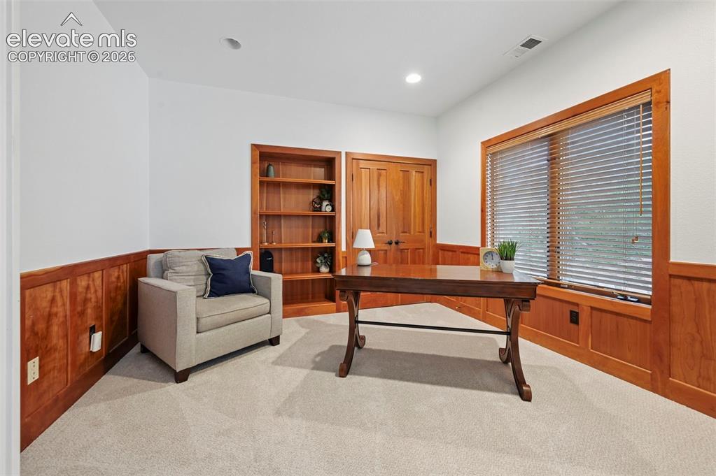 Image 27 of 45: Wood paneling and built-in shelving complement the light-toned carpeting