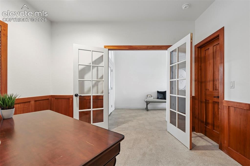 Image 28 of 45: Interior room featuring white walls with wood wainscoting, a light-toned ca
