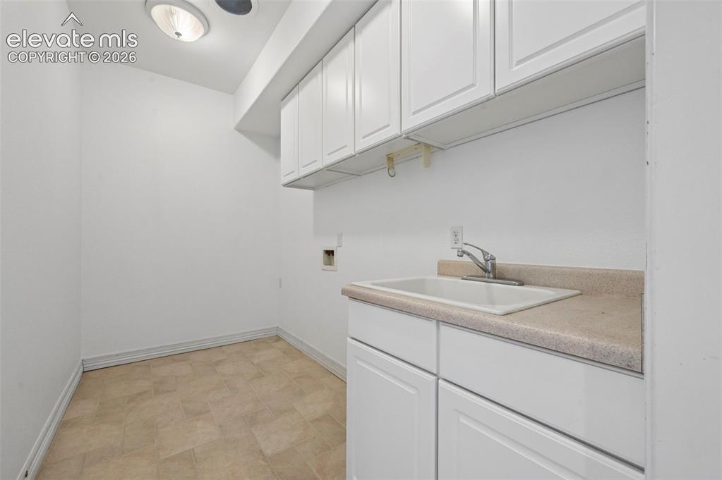 Image 34 of 45: Utility room featuring a utility sink, light beige countertop, and white ca
