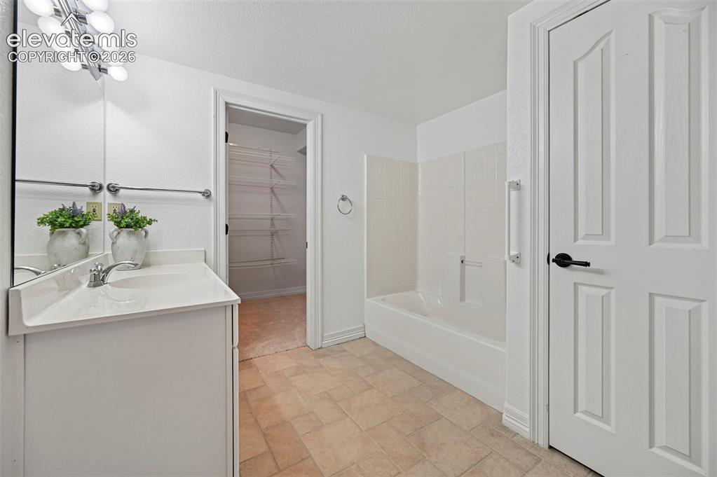Image 37 of 45: Bathroom vanity with integrated sink, chrome faucet, and overhead bar light