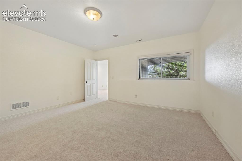 Image 38 of 45: Carpeted room featuring a window with horizontal blinds, a white paneled do