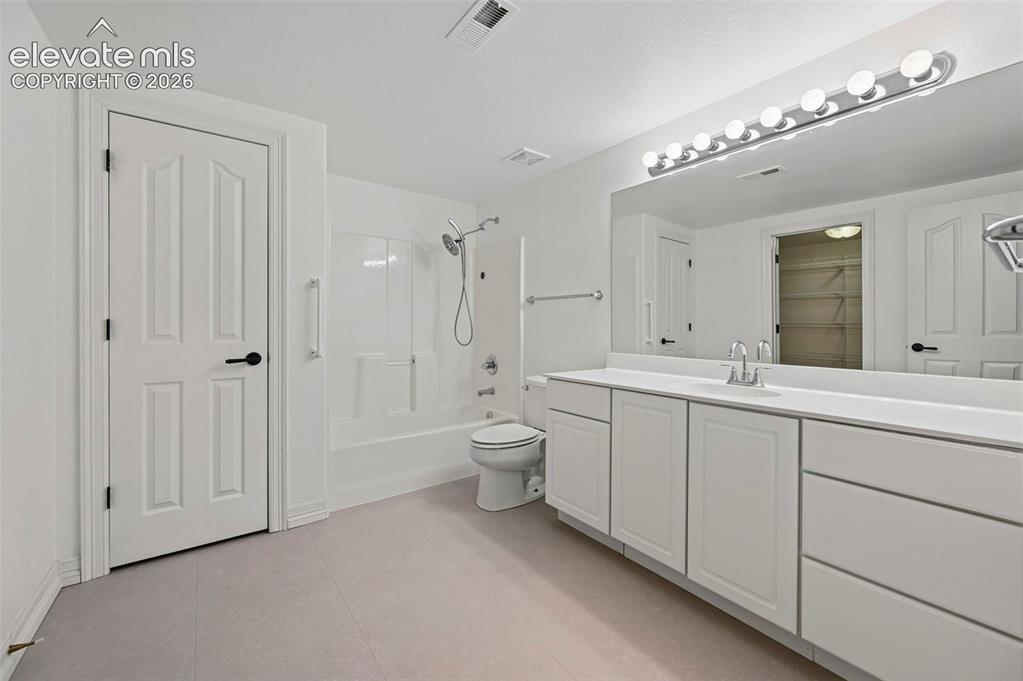 Image 39 of 45: Bathroom featuring a vanity with a white countertop and integrated sink, a