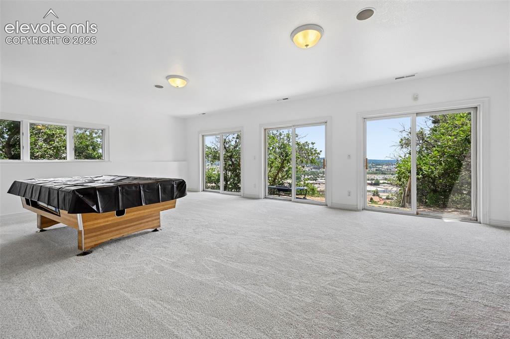 Image 40 of 45: Spacious recreation room featuring light gray carpet flooring and white wal