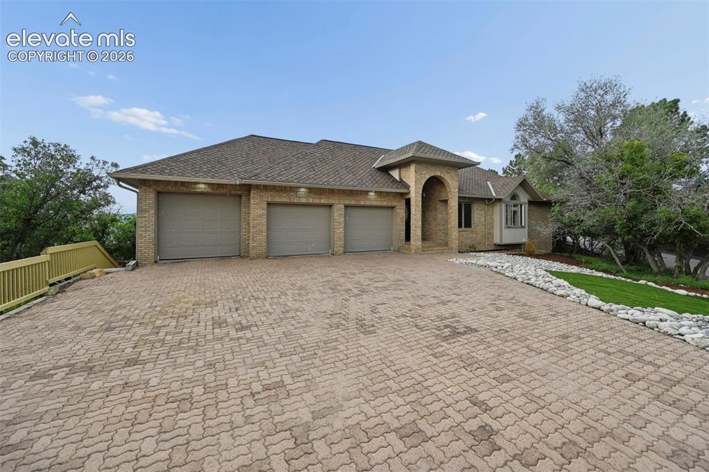 Image 8 of 45: Brick exterior featuring a three-car garage and a paved driveway