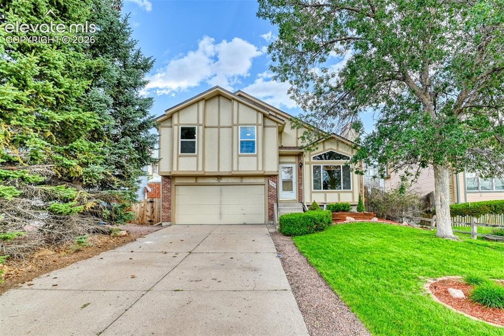 Caption: Split-level residence featuring a two-car garage, brick accents, and a large front window