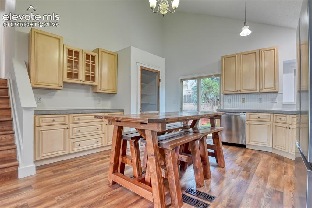 Image 10 of 48: Vaulted ceiling kitchen featuring wood-finish flooring, light-toned cabinet