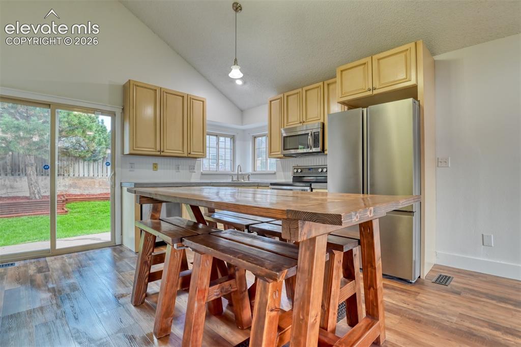 Image 11 of 48: Vaulted ceiling kitchen featuring wood-finish flooring, stainless steel app