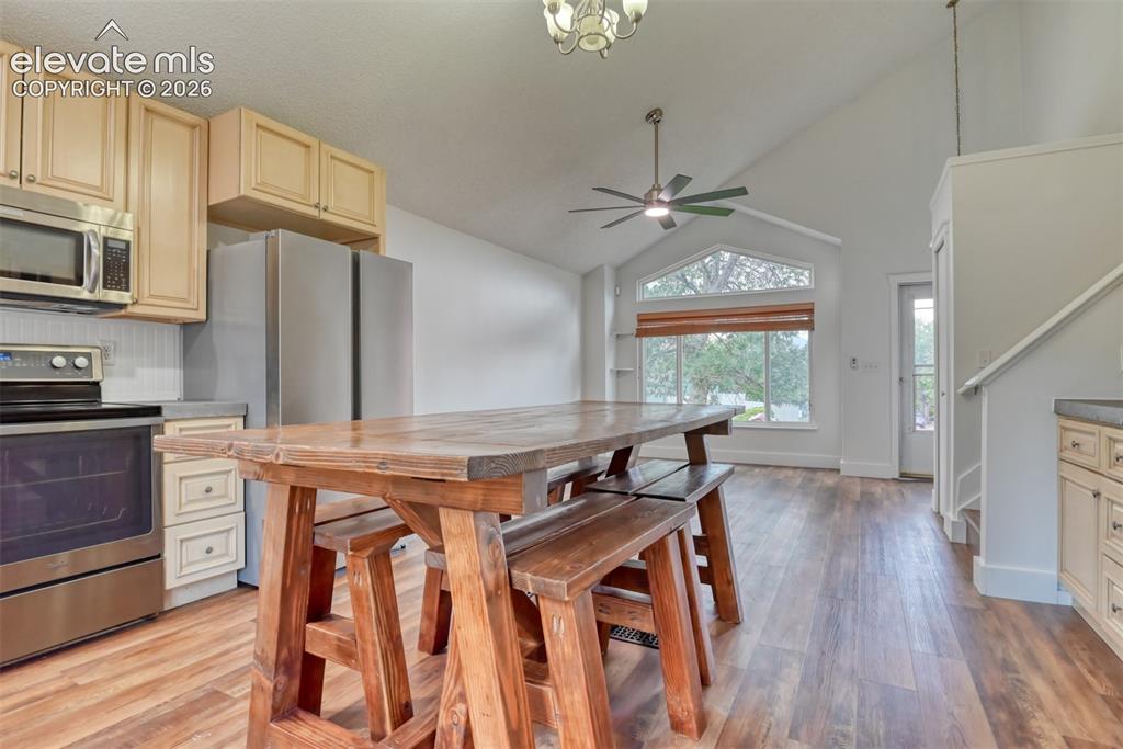 Image 12 of 48: Open-concept living area with vaulted ceilings, wood-finish flooring, and a