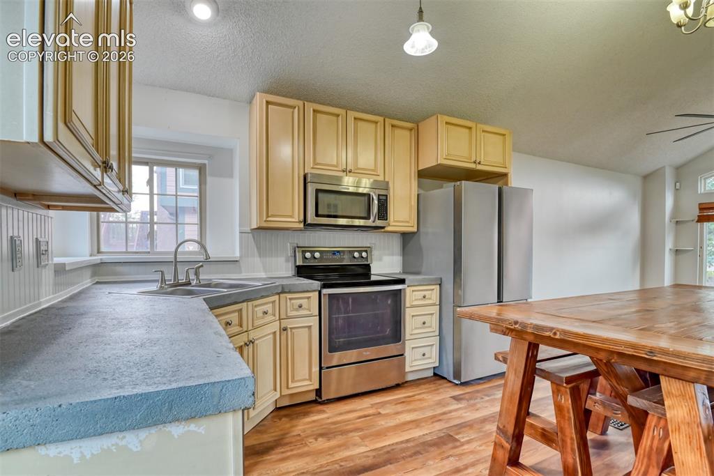 Image 13 of 48: Kitchen featuring wood-finish flooring, stainless steel appliances, light w