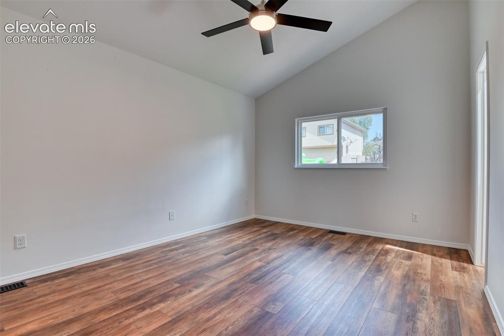 Image 18 of 48: Vaulted ceiling with a ceiling fan, wood-finish flooring, and a sliding win