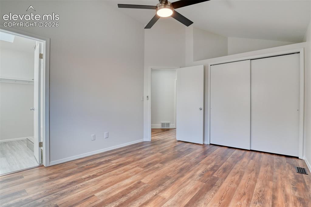 Image 20 of 48: Vaulted ceiling with a ceiling fan light fixture, wood-finish flooring, whi