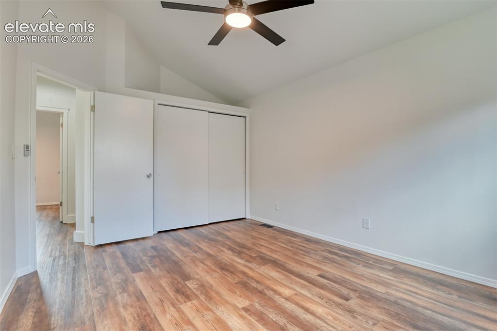 Image 21 of 48: Vaulted ceiling, wood-finish flooring, ceiling fan with integrated lighting