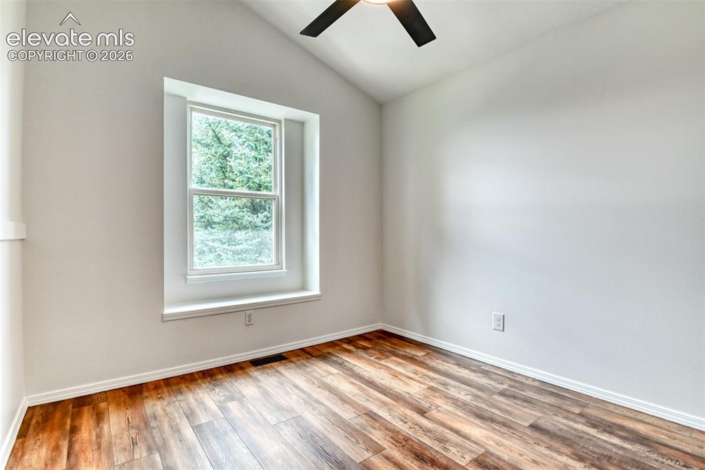 Image 25 of 48: Vaulted ceiling, wood-finish flooring, white walls, double-pane window, and