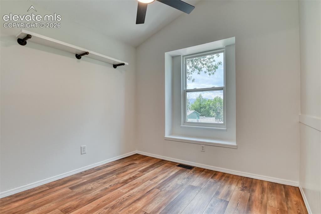 Image 29 of 48: Vaulted ceiling with a ceiling fan, wood-finish flooring, built-in shelving