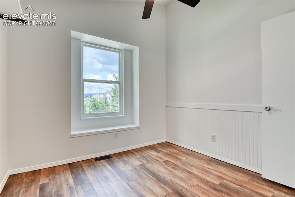 Image 32 of 48: Wood-finish flooring, white walls, white window trim, beadboard wainscoting