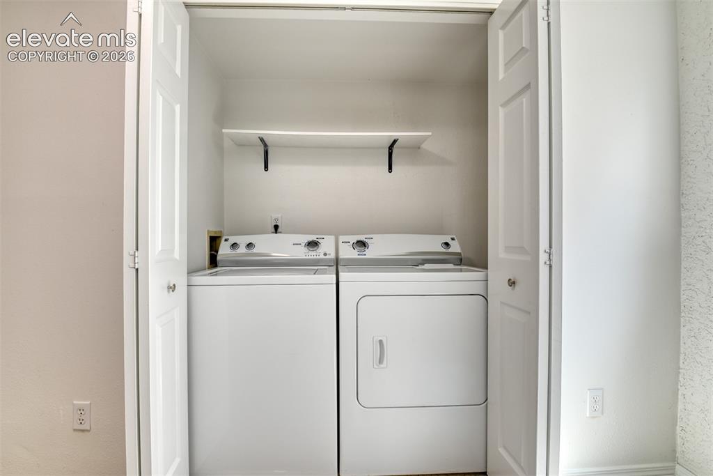 Image 39 of 48: Dedicated laundry closet featuring a white washer and dryer, a built-in she