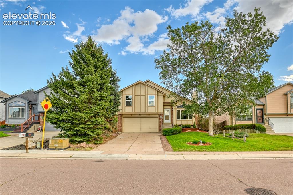 Image 4 of 48: Split-level residence featuring a two-car garage, established front yard la
