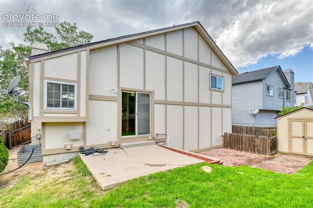 Image 42 of 48: Rear exterior featuring a patio, sliding glass door, and a detached shed