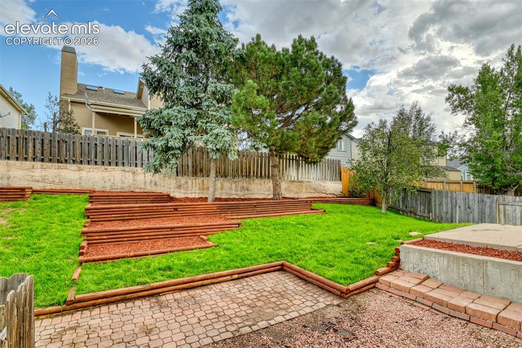 Image 45 of 48: Tiered landscaping featuring multiple levels of green lawn and wood-edged p