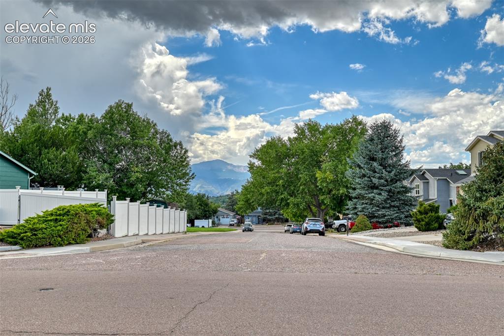 Image 48 of 48: Mountain backdrop, mature trees, residential street, white privacy fencing,