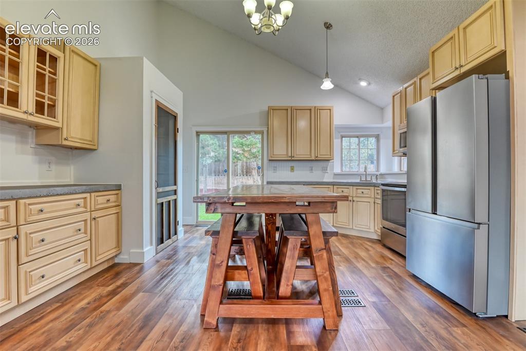 Image 9 of 48: Kitchen featuring wood-finish flooring, vaulted ceilings, and light wood ca