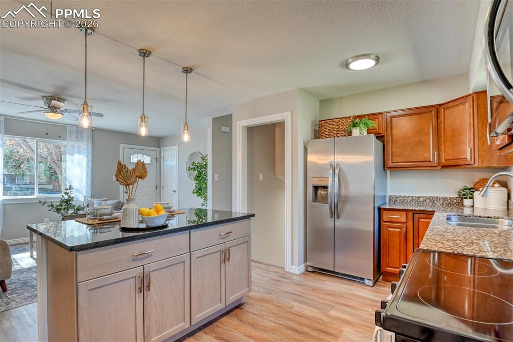 Image 12 of 39: The kitchen features a central island with a dark countertop and three pend