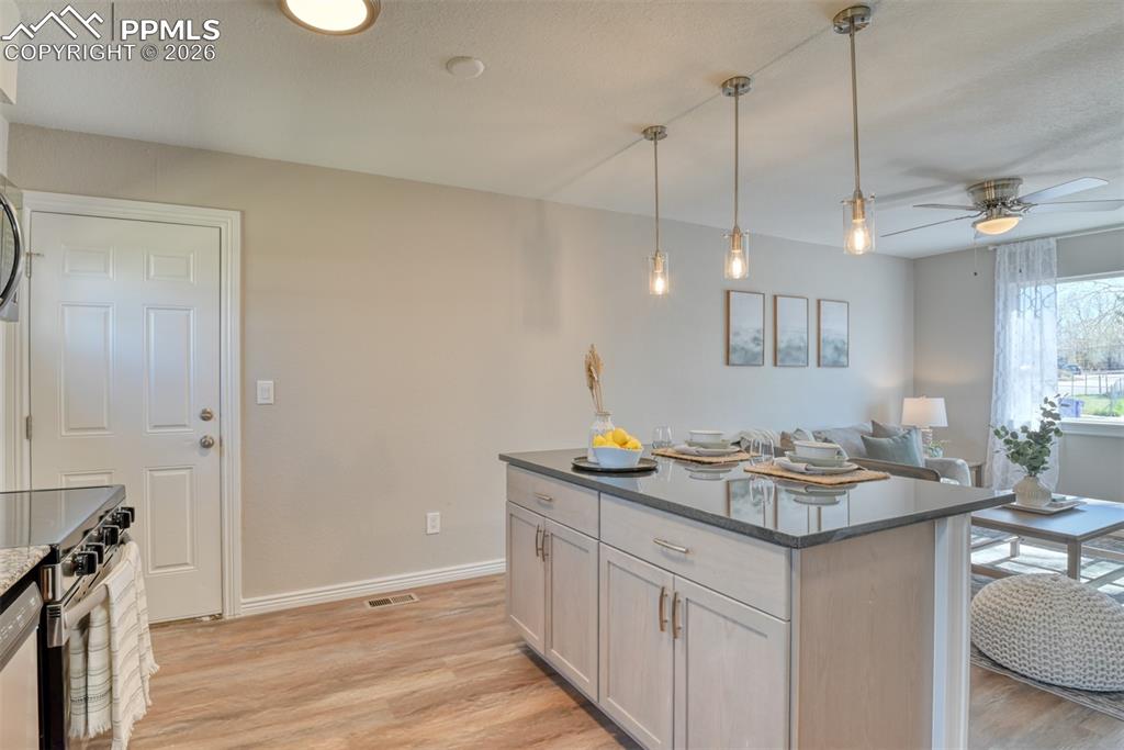 Image 13 of 39: The open-concept living area features a kitchen island with a dark countert