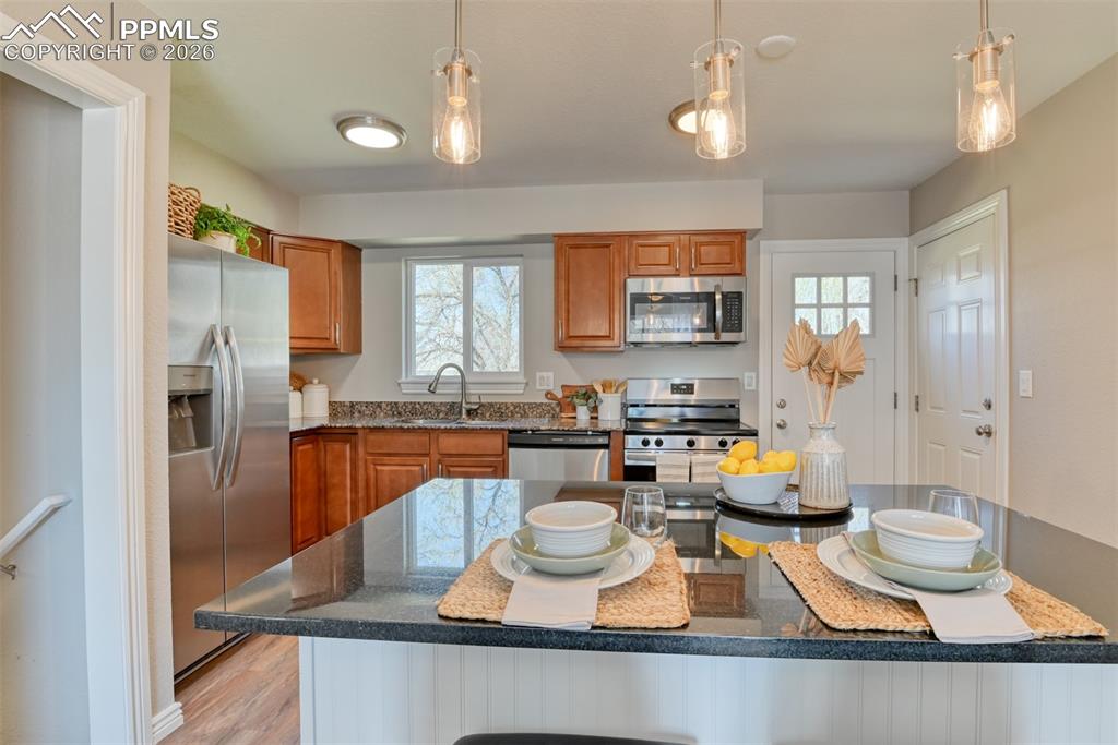 Image 14 of 39: Kitchen featuring stainless steel appliances, wood cabinetry, stone counter